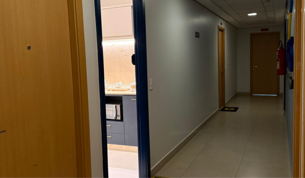 Corredor do andar comercial que dá acesso à sala da Voltacred, com a porta de entrada aberta.